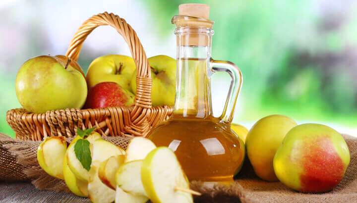 Apple cider vinegar in glass bottle and ripe fresh apples